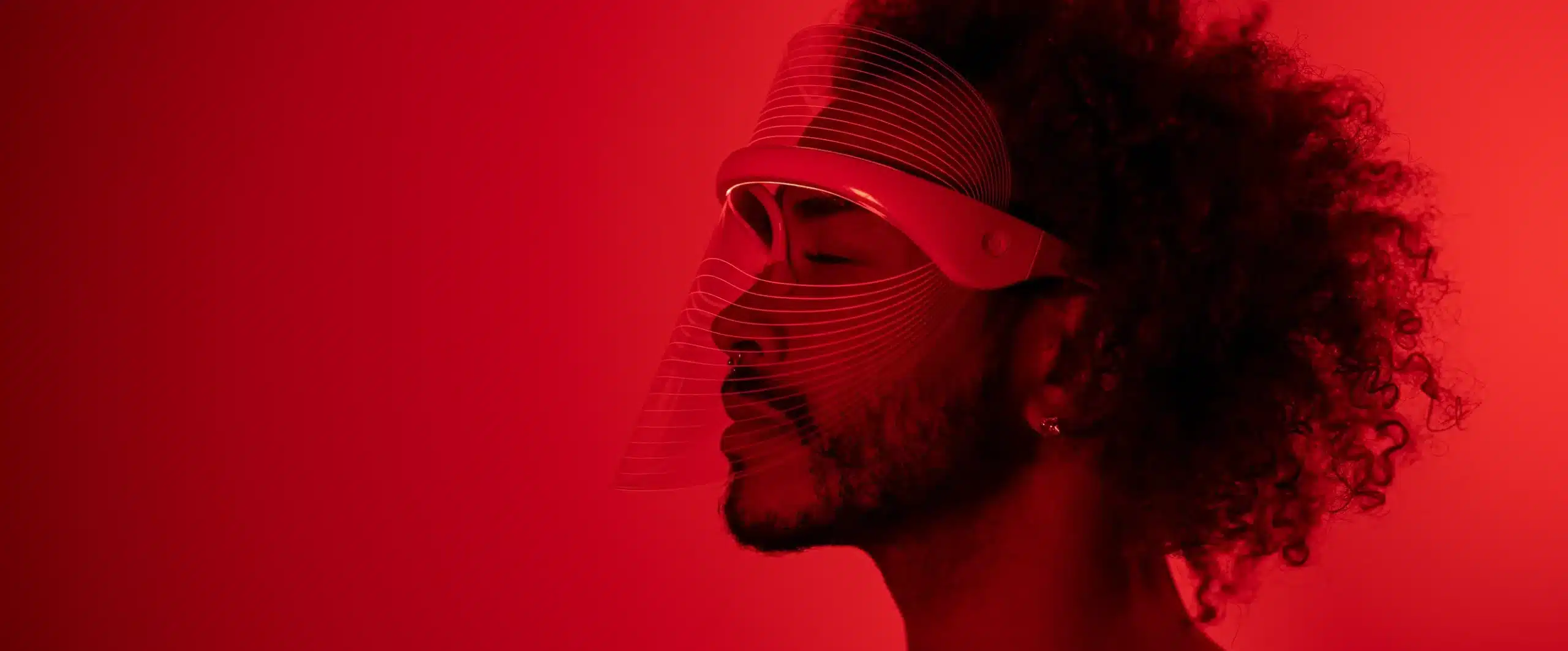 A side profile of a man wearing a red light therapy mask