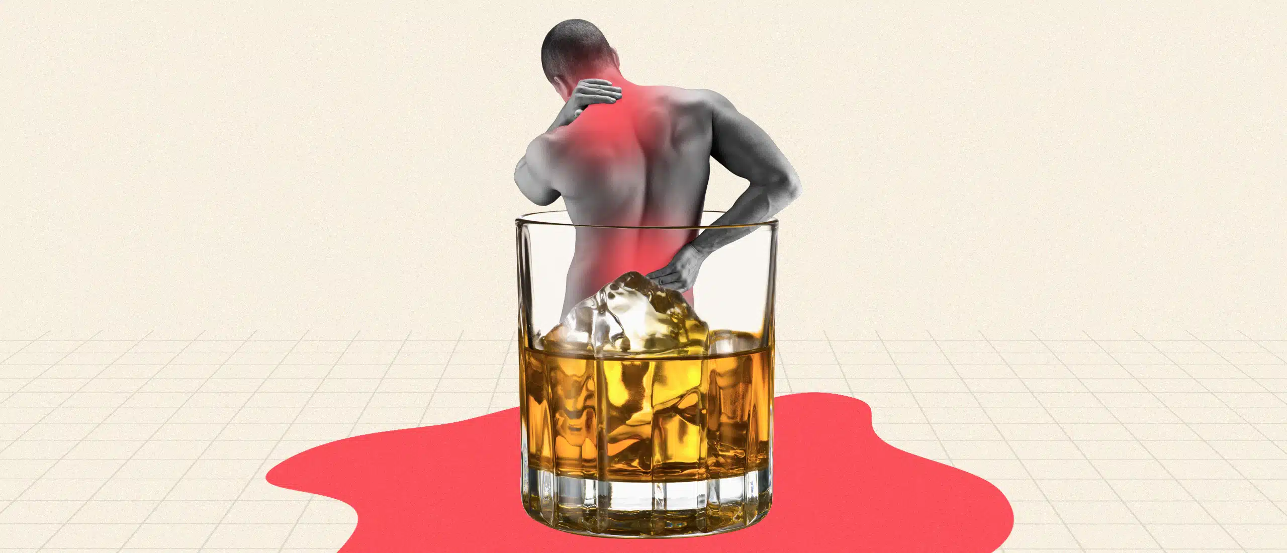 A man holding his back near a glass of whiskey