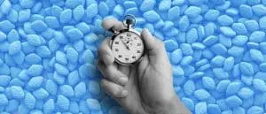 hand holding stop watch over a pile of medications