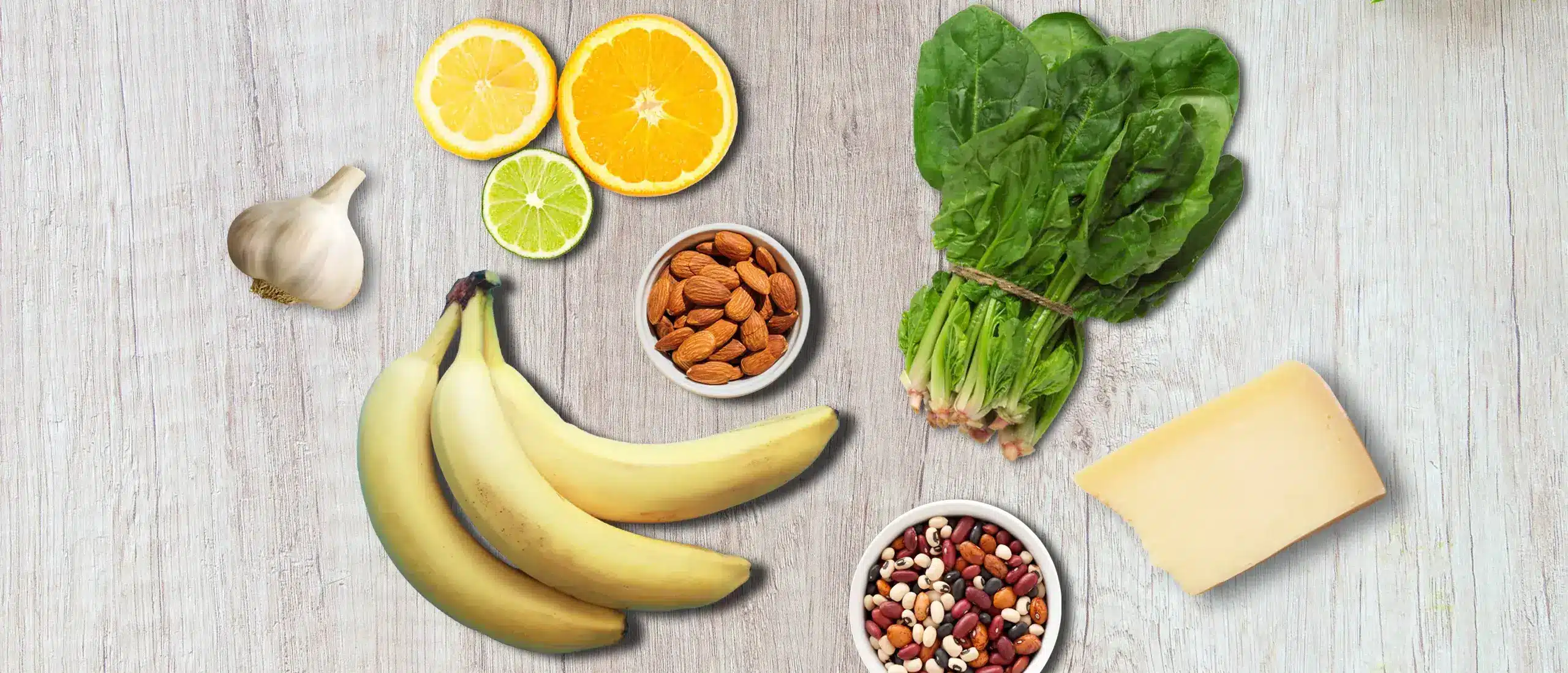 Butyrate foods—citrus, bananas, almonds, beans, lettuce, and hard cheese—displayed on a wood board.