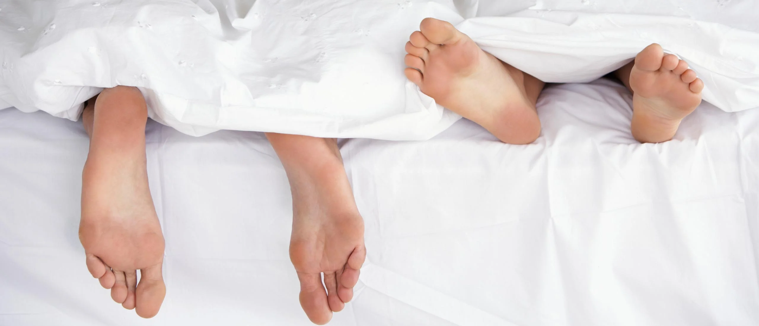 couple in bed with feet sticking out of the covers