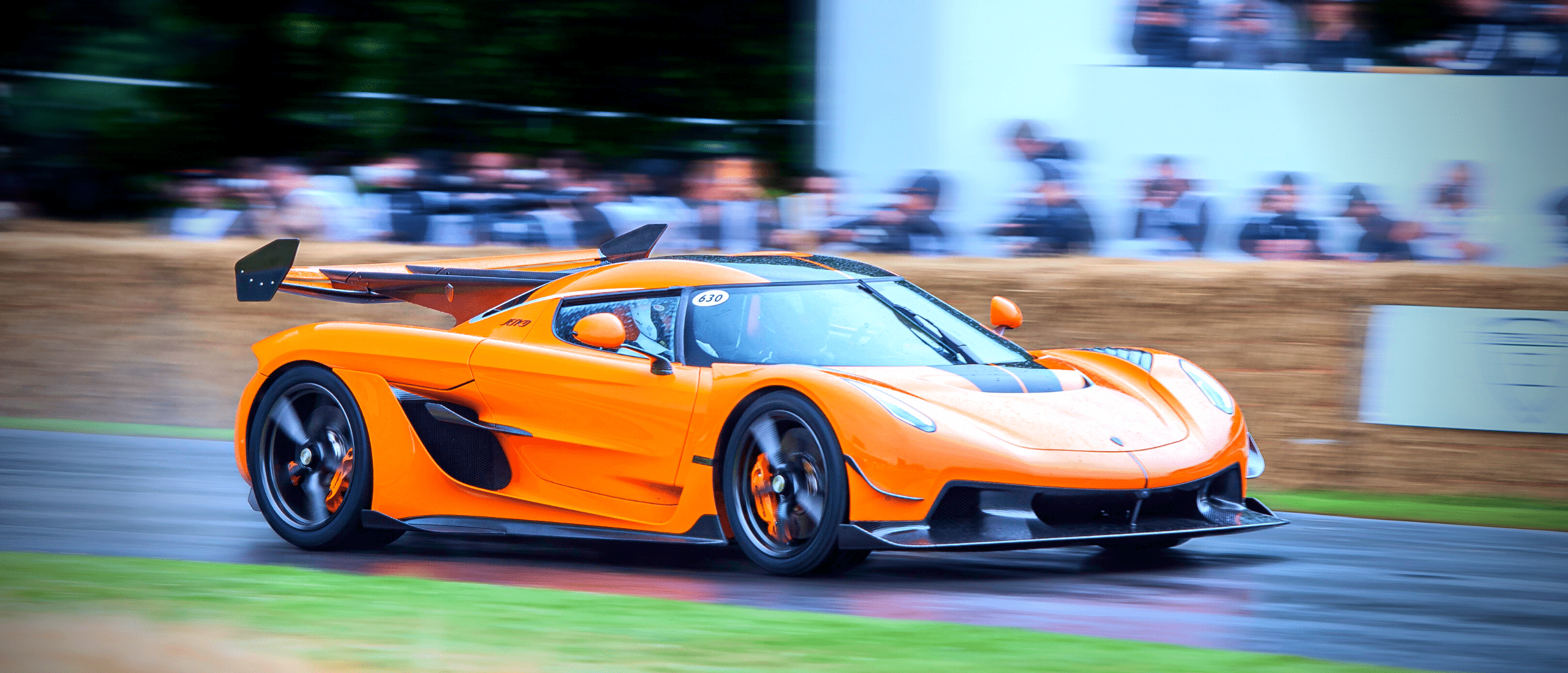 A bright orange sports car zooms around a track