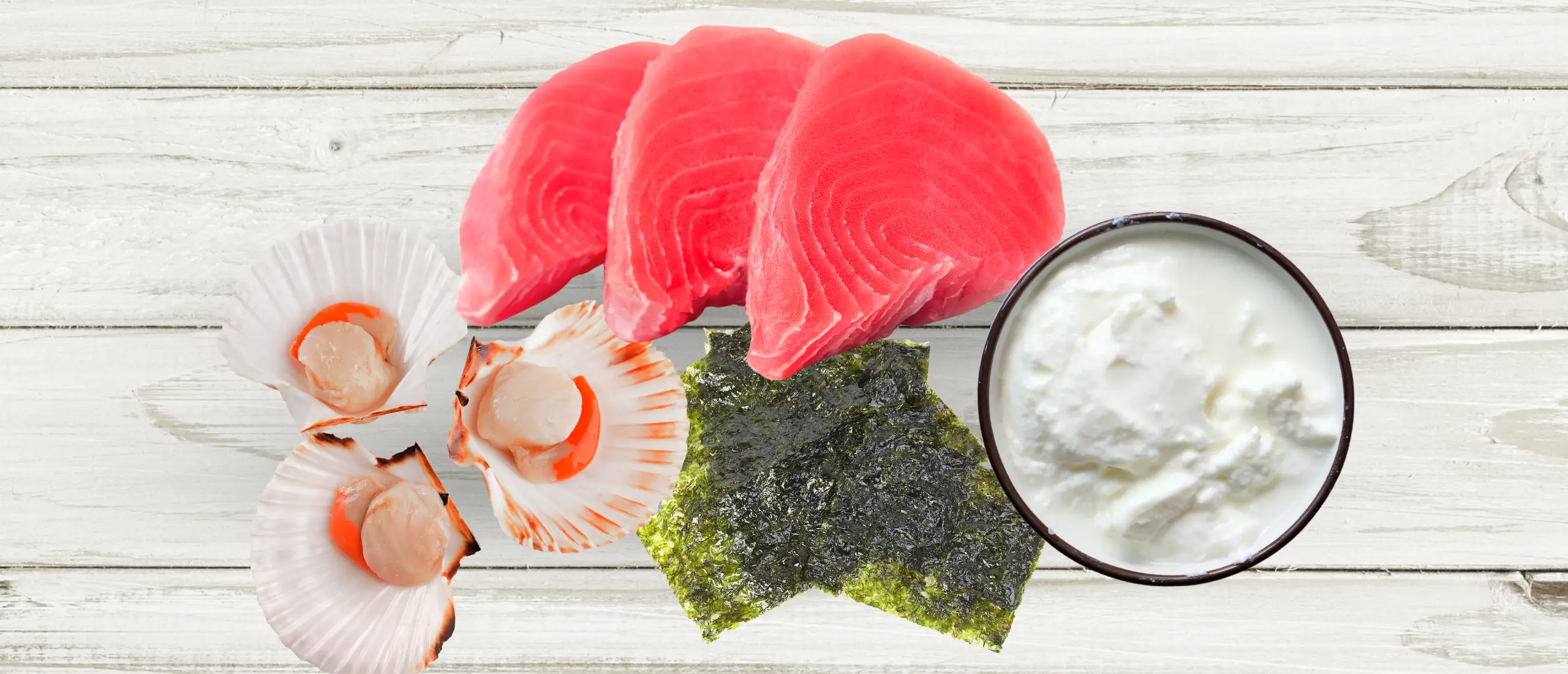 Shellfish, tuna, seaweed, and yogurt (all foods high in taurine) displayed on a wite wood board.
